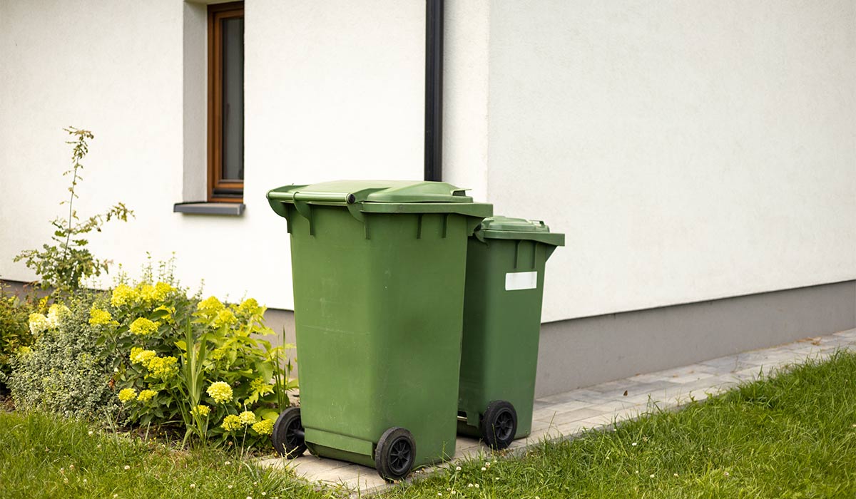 Two Big empty green plastic trash garbage bin in front of the modern house. Plastic pollution problem.; Shutterstock ID 2490258959; purchase_order: -; job: -; client: -; other: