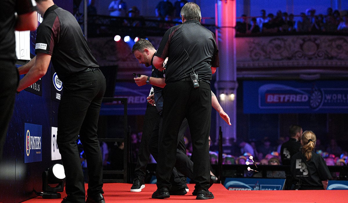 Cameron Menzies is helped from the stage after being taken ill during the match during day five of the 2026 Betfred World Matchplay. Pic: Getty
